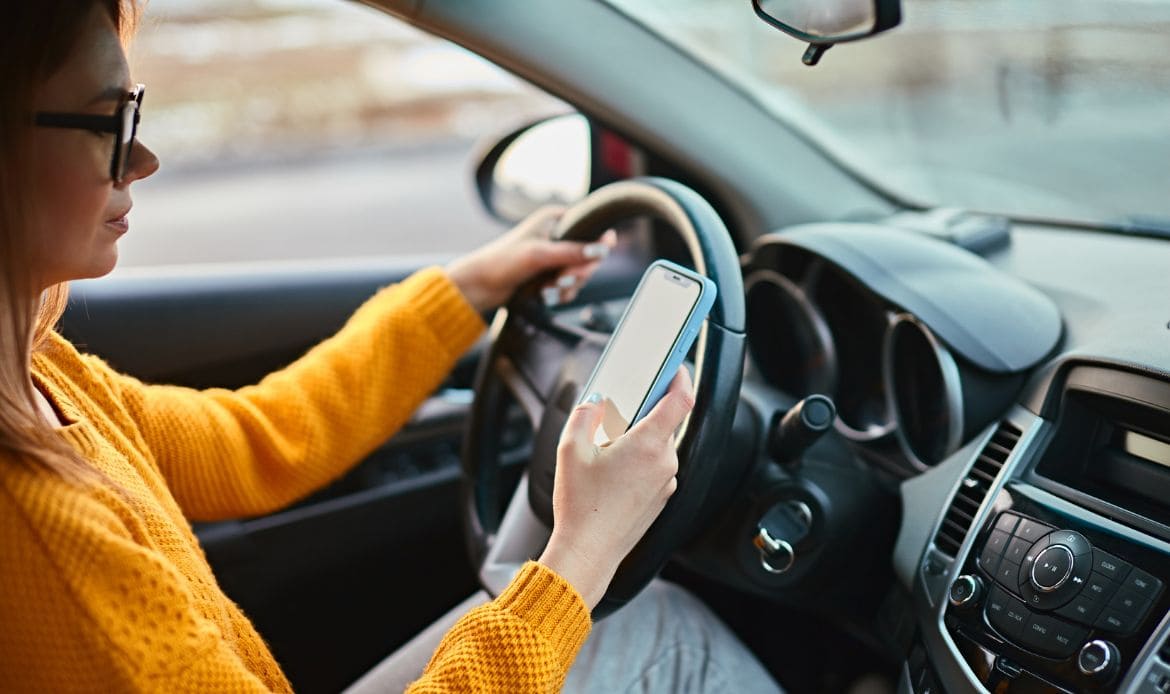 Persona viendo su celular en el auto